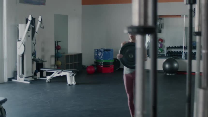 A woman is doing weight training in the gym