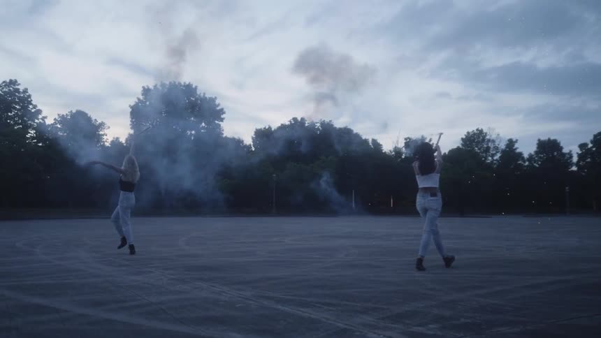 Two women shoot flares out in a parking lot