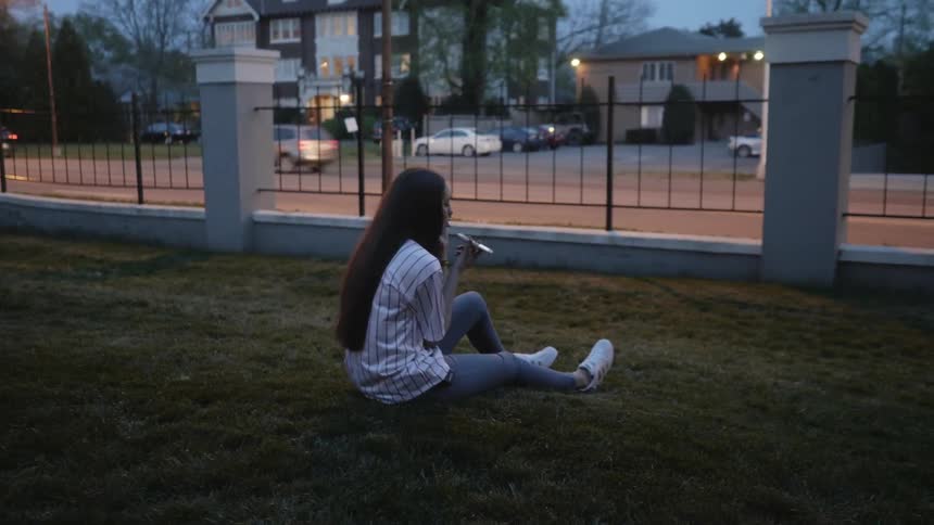 Woman sits in a yard talking into her phone