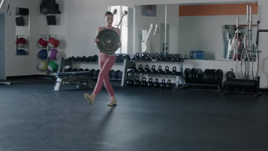 Woman using a large weight-plate to exercise in a gym