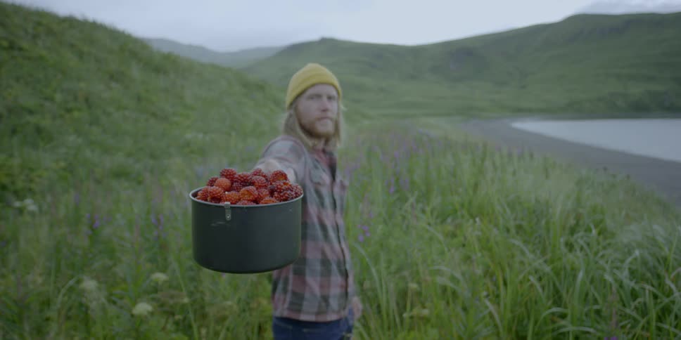 A man holds a pot full of berries