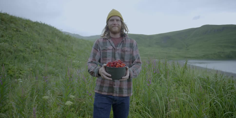 A man holds a pot of berries and smiles