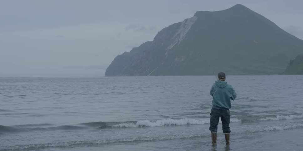 A man fishes in the ocean from the beach