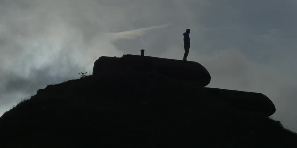 Silhouetted hiker stands on a building