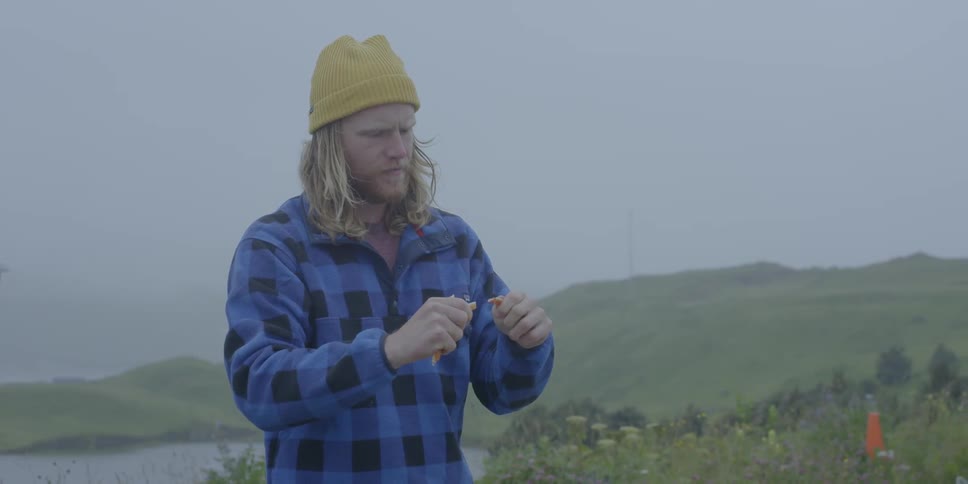 Man snaps a crab leg and takes a bite outside on a rainy day