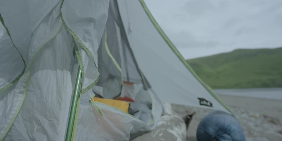 The flaps on a tent are blowing in the breeze during the day