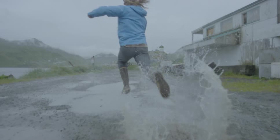 Man in boots splashes in puddles during a rainstorm