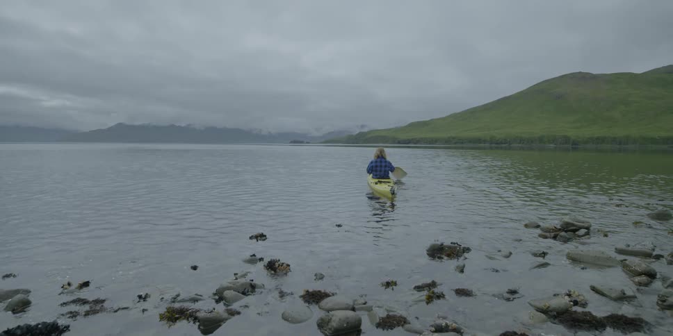 Man paddles a kayak on a cloudy day