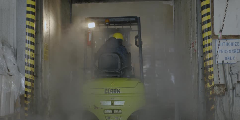 A man drives a forklift through a warehouse