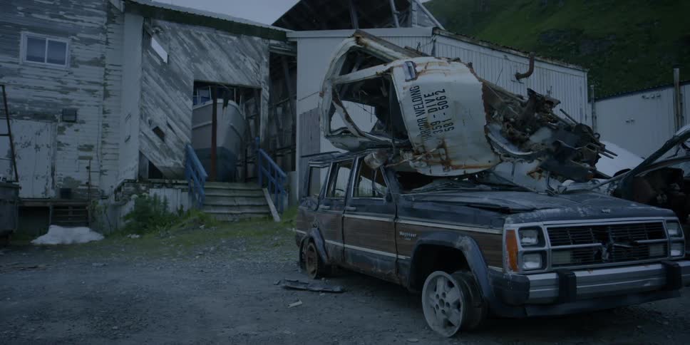 Wrecked vehicles in front of an old building