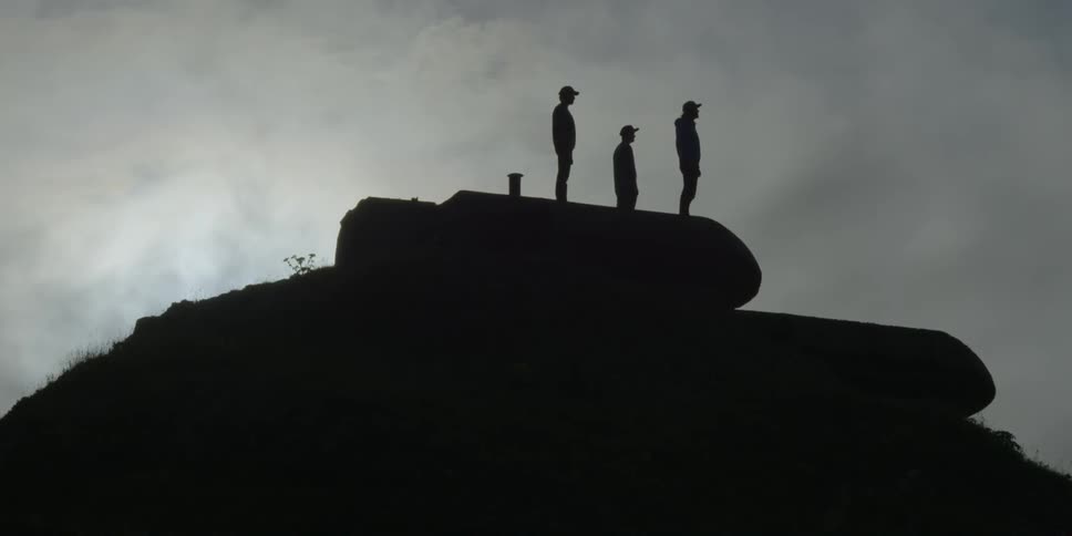 Silhouetted hikers stand on a building