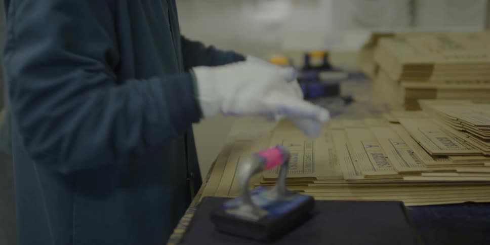Workers stamp onto cardboard boxes