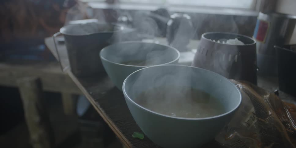 Steam pours from bowls in a cabin