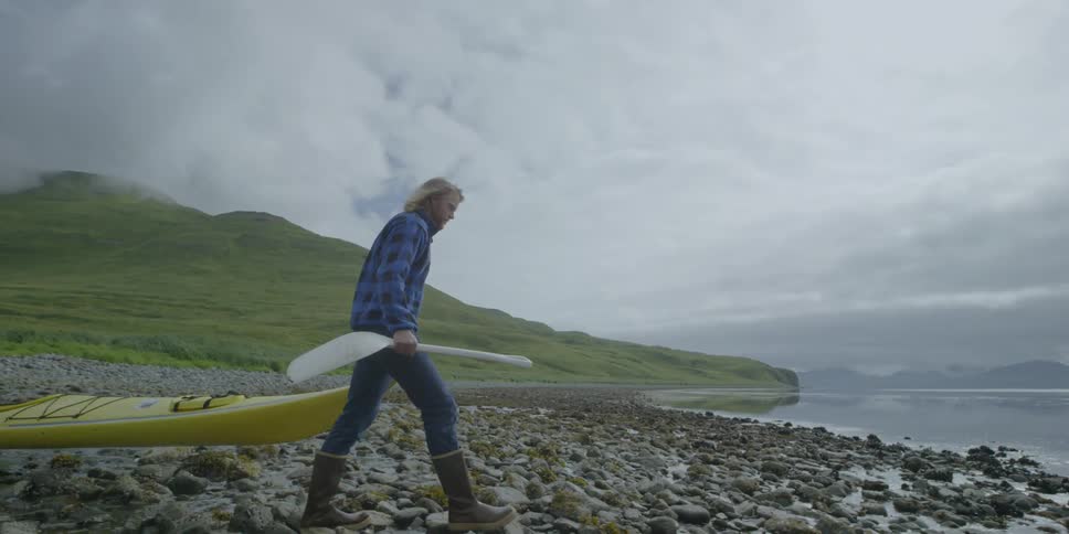 A man drags a kayak on the beach shore