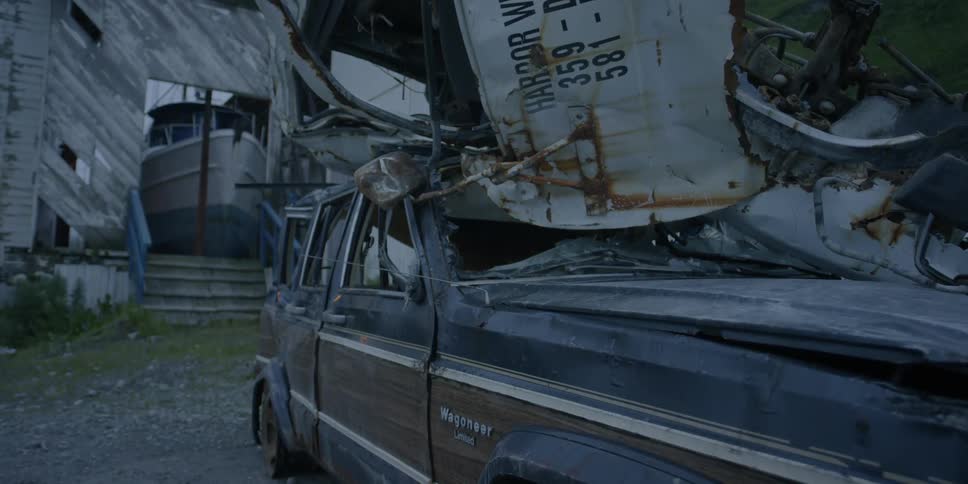 Debris is stacked on top of an old car