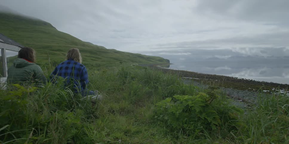 People sit beside a cabin near the ocean