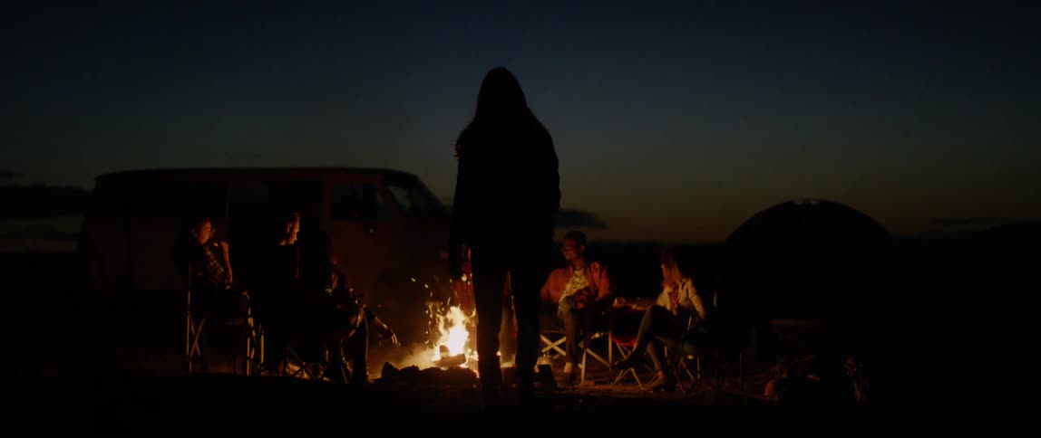 A group of people sit around a campfire