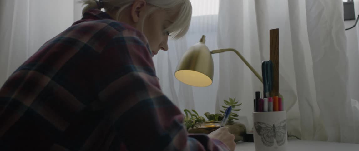 A woman writes at a desk