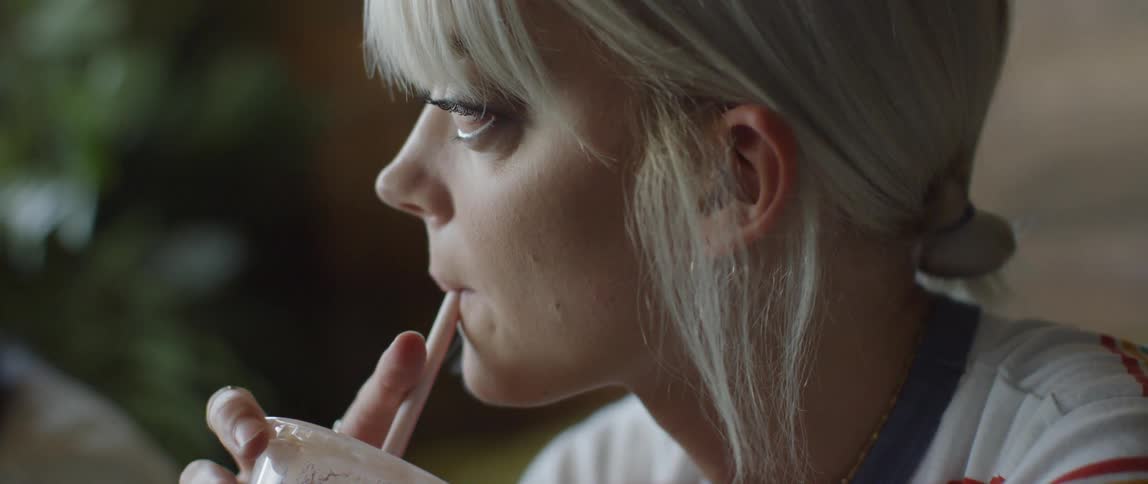 A woman slowly drinks from a straw