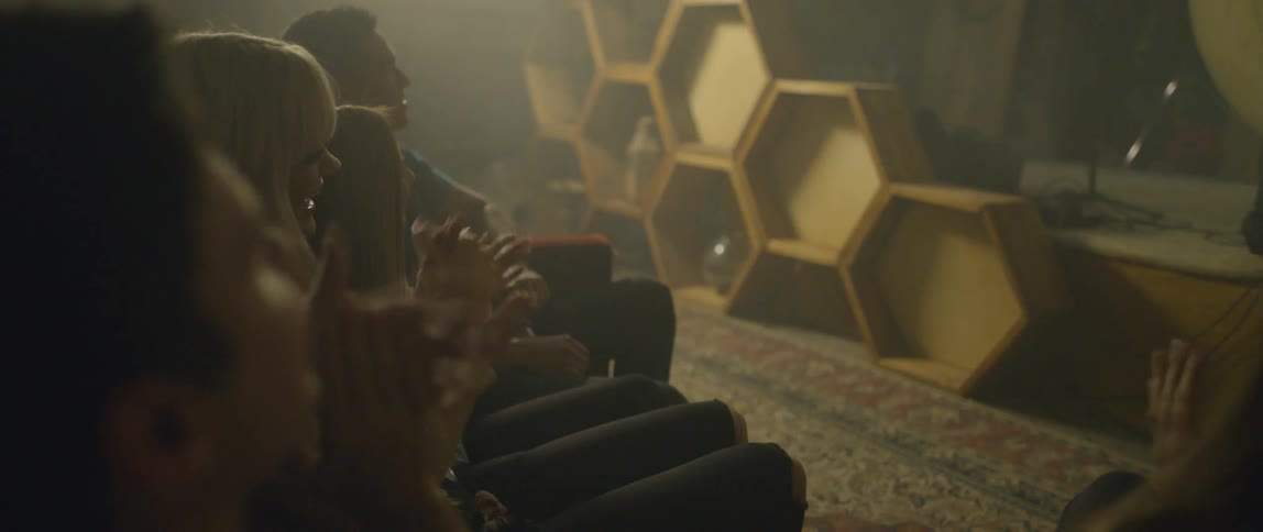 A group of people clap from a couch at a karaoke bar