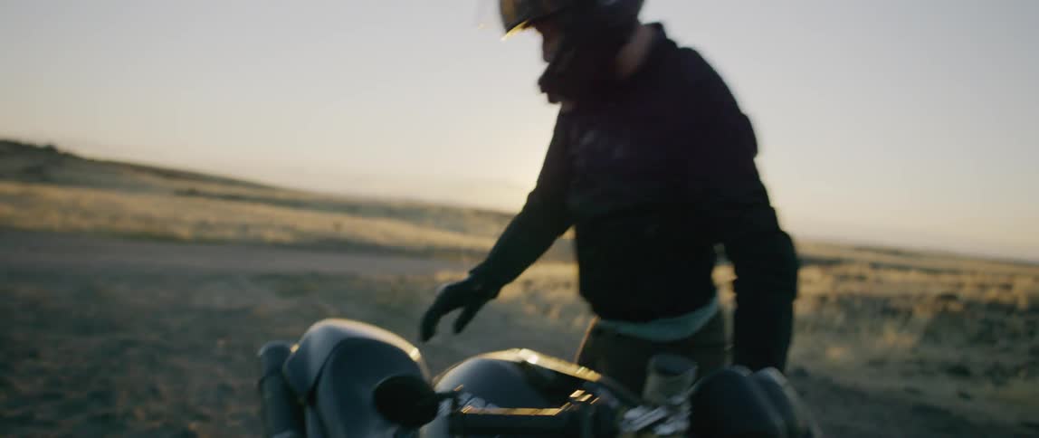 Two people ride motorbikes in the country at sunset