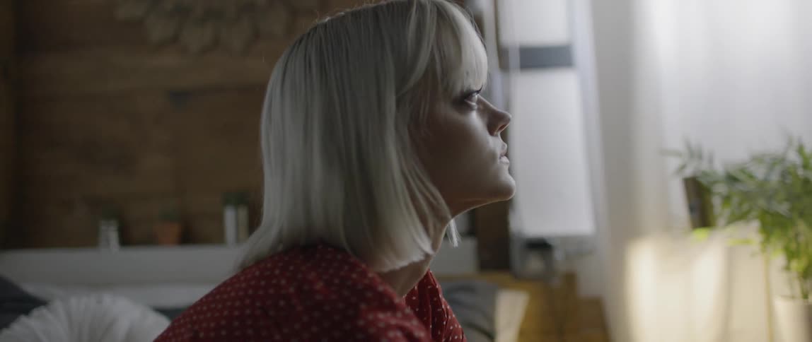 A woman sits on a couch and leans forward