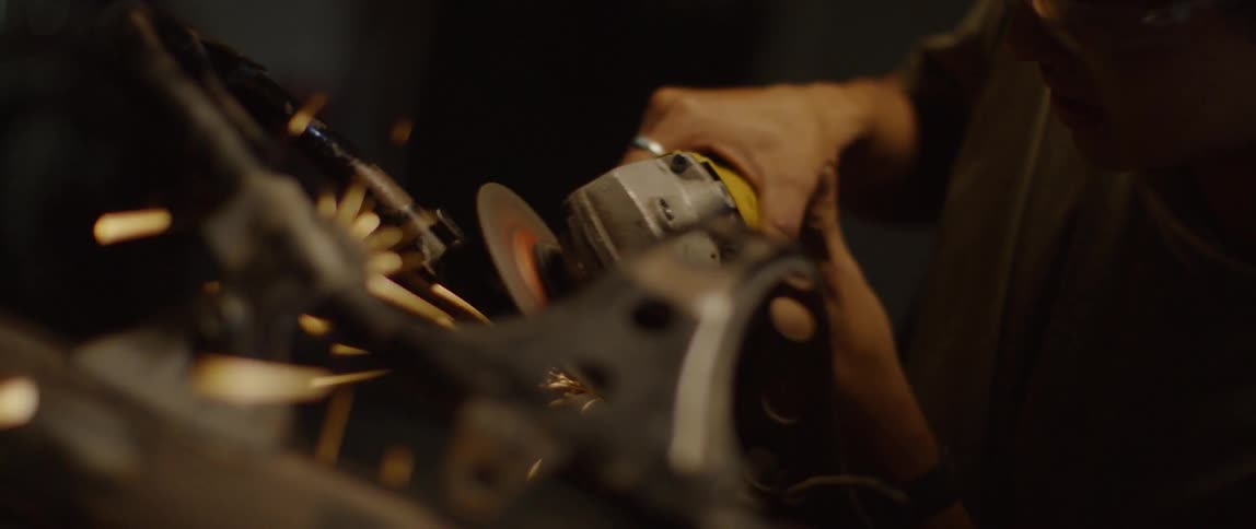 A man grinds steel with a grinding wheel