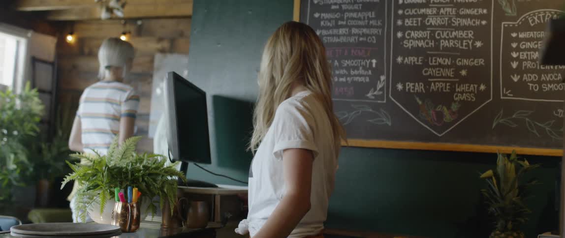 Woman stands behind the counter at a coffee shop