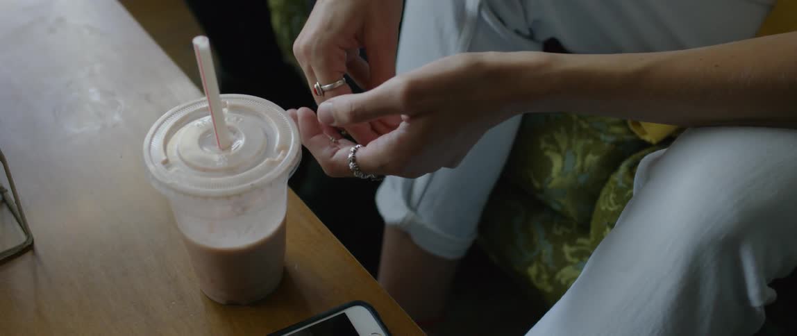 Person plays with their hands and picks up a beverage
