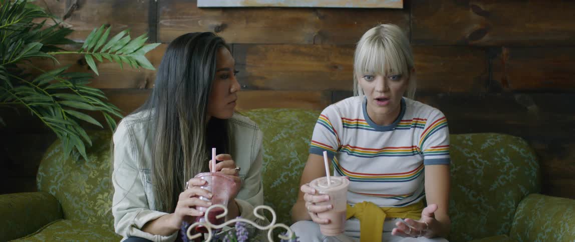 Two women holding cups are talking