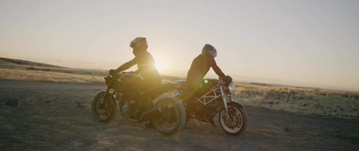 Two people ride off on their motorcycles