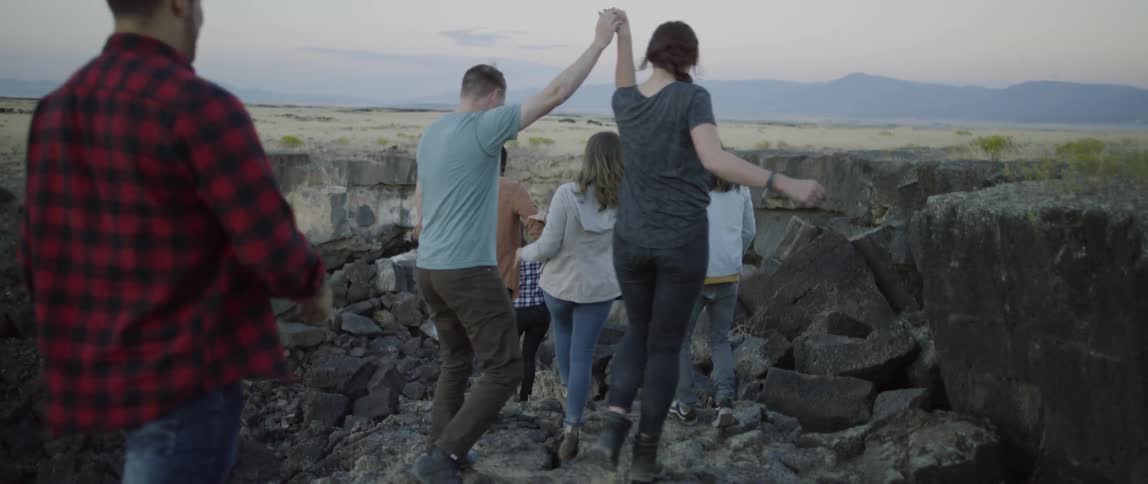 A group of people walk towards a cave