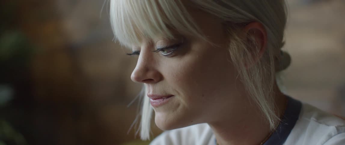 A woman is pursing her lips and nodding as she sits indoors during the day