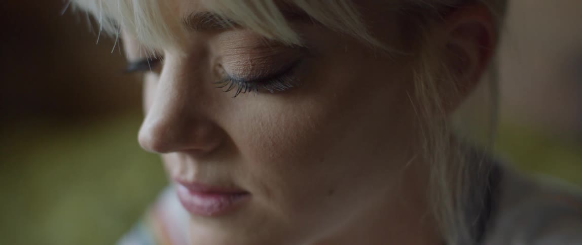 A blond haired woman shakes her head and begins to smile