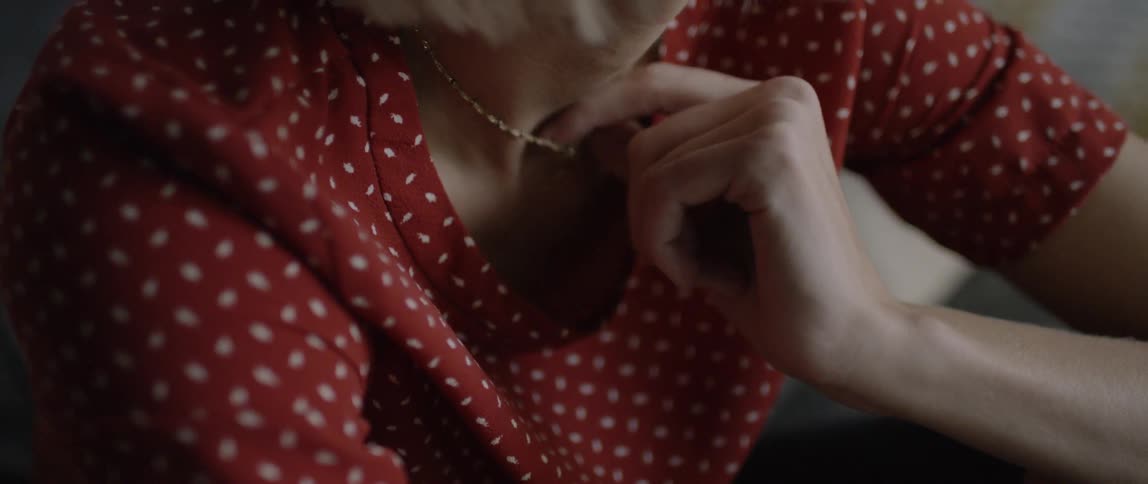 A blond haired woman fidgets with her necklace