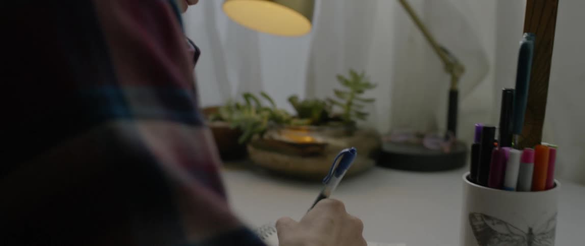 A woman writes in a notebook on her desk