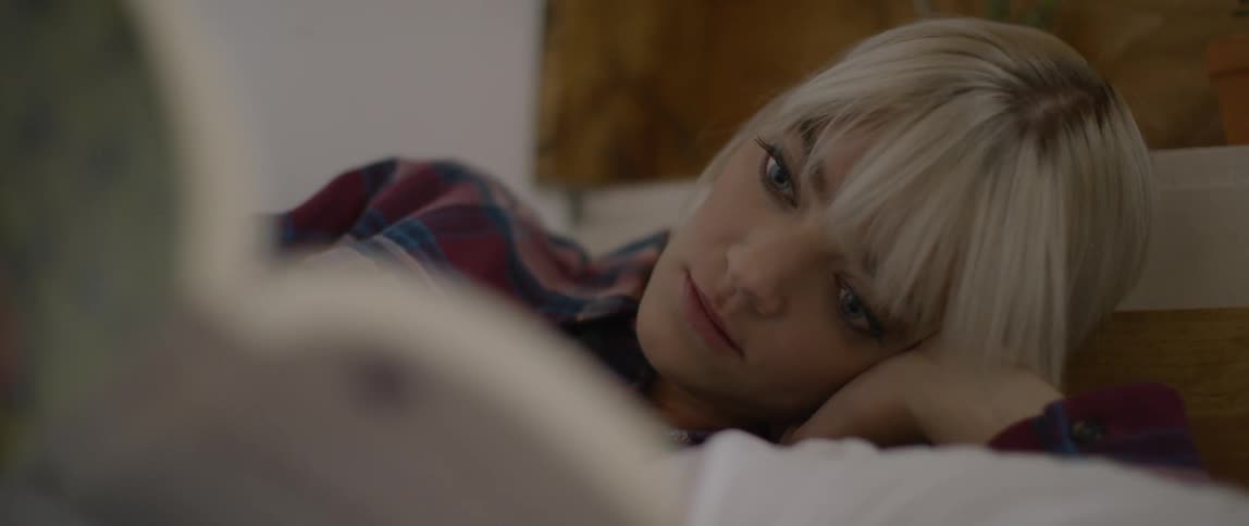 A blond haired woman lays in bed