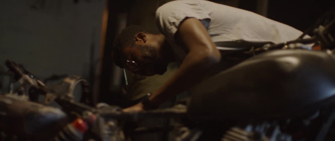 Two men work on a motorcycle in a garage