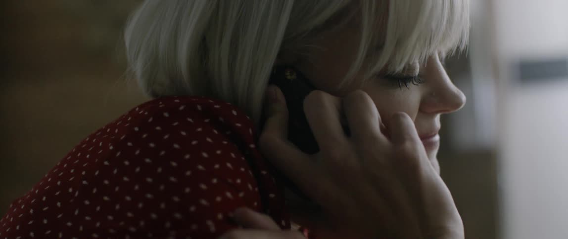 A woman sits curled up while talking on the phone