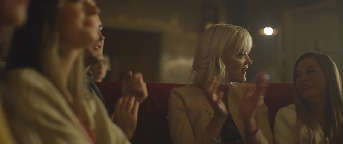 A group of people clap from a couch at a karaoke bar