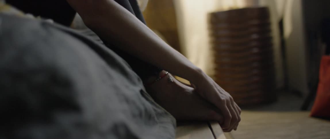 A woman sits curled up on the bed