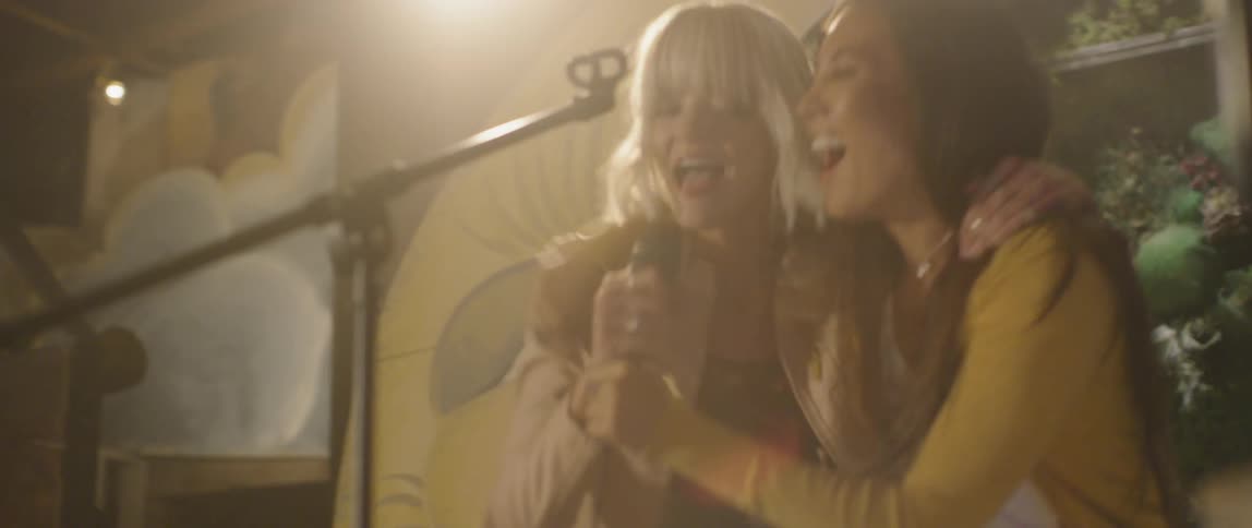 A woman performs karaoke on stage and pulls a friend on stage with her