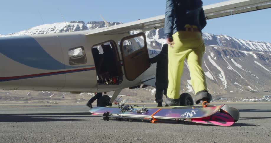 People unpack the small plane by the mountain