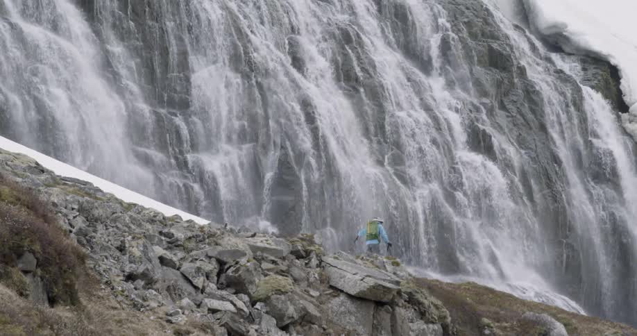 A man is hiking along the waterfall