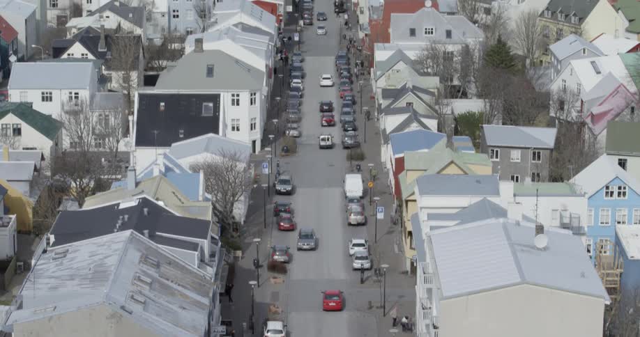 Cars are driving past the homes on this long avenue in city