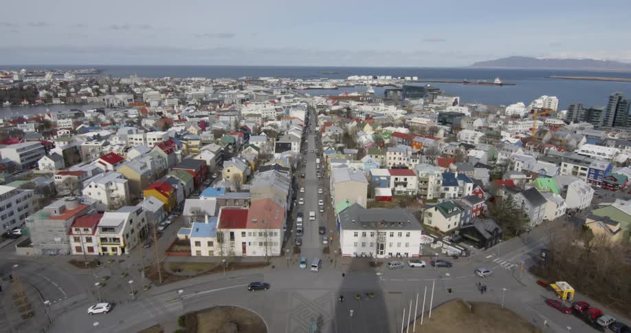 Cars are driving on the streets of a small town on the coast during the day