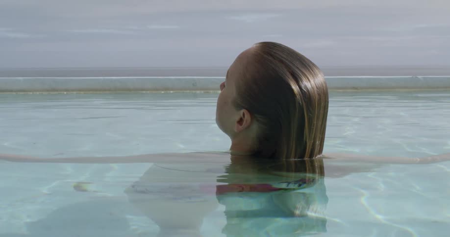 A woman is swimming in a pool next to the ocean