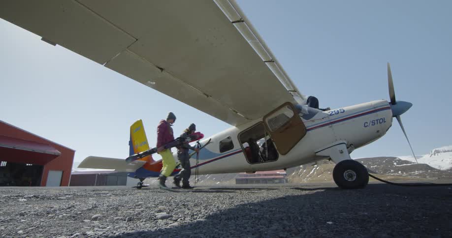 People carry their ski equipment over to a waiting plane
