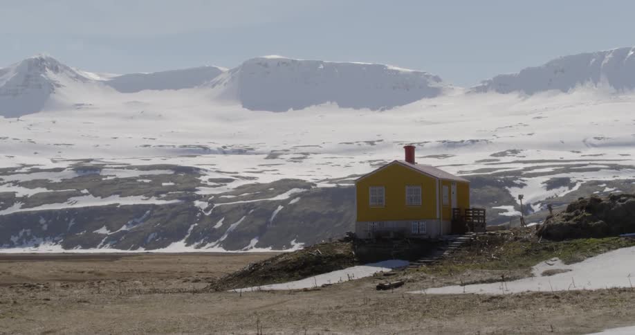 A bright yellow house in the middle of a frozen landscape