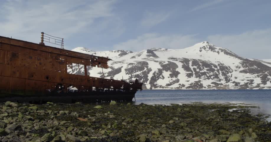A rusted boat sits on the side of the water